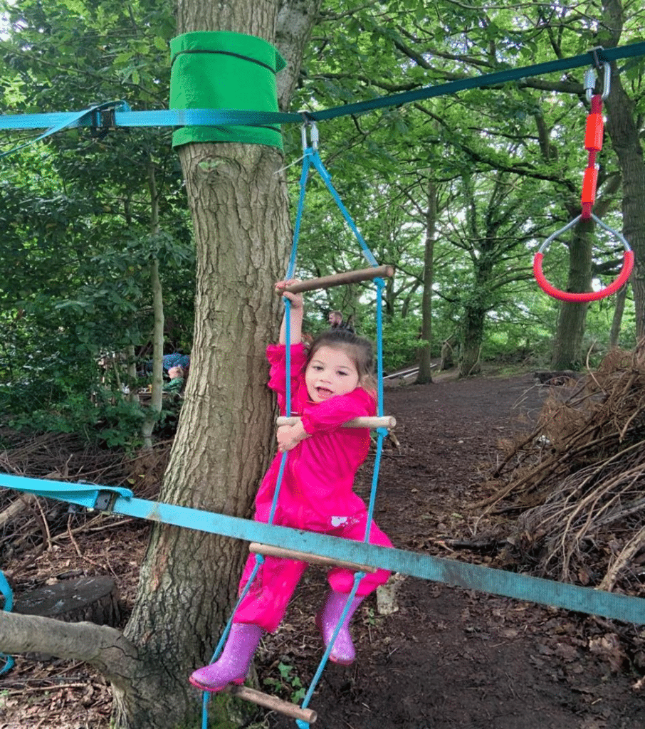 Girl climbing a rope ladder in a forest