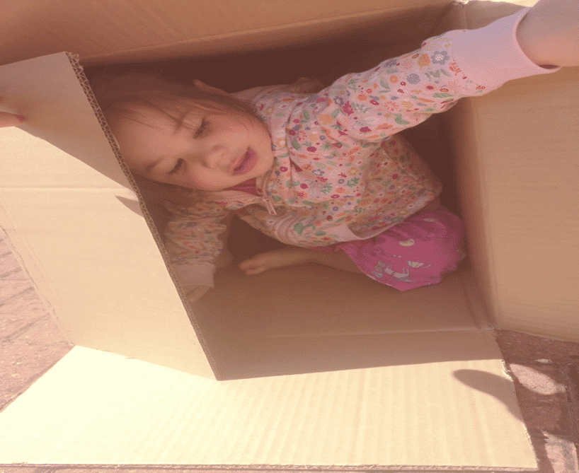 Girl with an enveloping schema hiding in a cardboard box